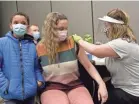  ?? SARAH C. TOBIAS/USA TODAY NETWORK ?? In Ohio, middle school choir teacher Samantha Speakmon, center, gets a first dose of Pfizer’s COVID-19 vaccine from Licking County Health Department nurse Brittany Goldsberry, right, on Feb. 10.