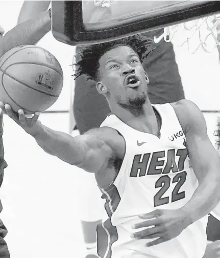  ?? MATT YORK/AP ?? Heat forward Jimmy Butler (22) is fouled by Suns forward Torrey Craig, left, as forward Cameron Johnson (23) looks on during Tuesday’s game in Phoenix.