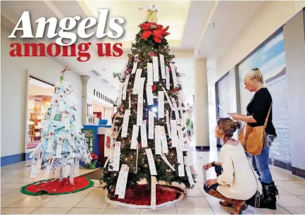  ?? [PHOTOS BY NATE BILLINGS, THE OKLAHOMAN] ?? Angela Thompson, kneeling, and her mother-in-law, Nancy Morton, select angel tags from a Salvation Army Angel Tree on Wednesday at Penn Square Mall in Oklahoma City.