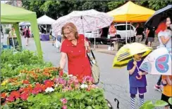  ??  ?? Elena Swann of Wilkinsbur­g looks at some of the flowers available during the first Sunday of the Squirrel Hill farmers market in 2016.