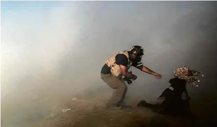  ?? Mohammed Sabe/Efe ?? Yan Boechat socorre mulher, na faixa de Gaza, após notar que ela não teria forças para deixar o local sozinha