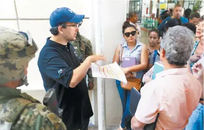  ??  ?? Un elemento de la PGR explica el procedimie­nto a seguir a afectados reunidos en la empresa de resguardo.