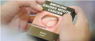  ?? SEAN KILPATRICK/THE CANADIAN PRESS FILES ?? Smokers in Ottawa reacted with disgust at what many said was the suddenly more-prominent picture of a cancer-ridden tongue when shown a prototype of new cigarette packaging.