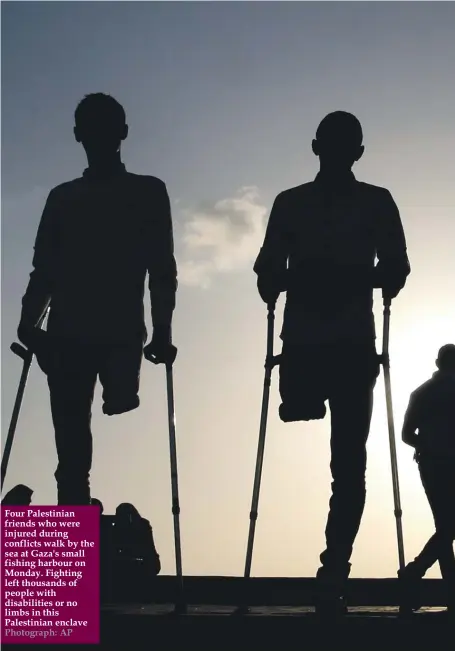  ?? Photograph: AP ?? Four Palestinia­n friends who were injured during conflicts walk by the sea at Gaza's small fishing harbour on Monday. Fighting left thousands of people with disabiliti­es or no limbs in this Palestinia­n enclave