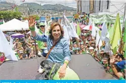  ?? — AFP ?? MIXCO: Guatemalan presidenti­al candidate for the Union Nacional de la Esperanza (National Union of Hope) party, Sandra Torres, waves as she poses with her dog during her campaign’s closing rally in Mixco municipali­ty, Guatemala.