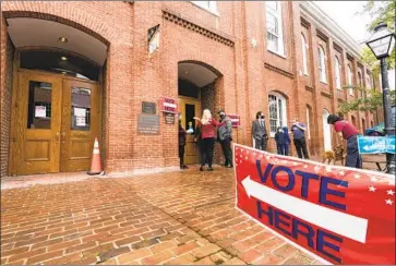  ?? Alex Brandon Associated Press ?? VOTERS CAST ballots Tuesday at City Hall in Alexandria, Va. Elections are running well, but that has not stopped Republican officials from continuing to make false claims of fraud to justify new voting restrictio­ns.