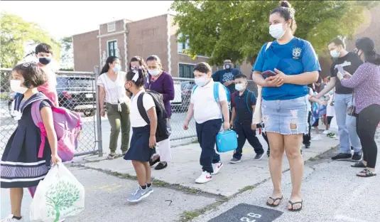  ?? ANTHONY VAZQUEZ/SUN-TIMES ?? Students and parents wait outside Alessandro Volta Elementary in Albany Park on Monday, the first day of class for the new school year.