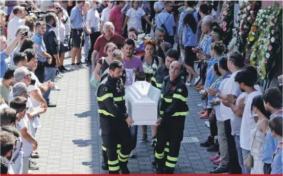  ??  ?? Firefighte­rs carry the coffin of nine-year-old Giulia Rinaldo outside the gymnasium where the state funeral service for some of the victims of the earthquake that hit central Italy last Wednesday took place, in Ascoli Piceno, Italy yesterday
