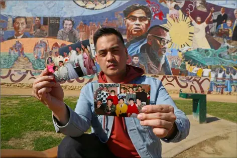  ?? PHOTO ?? In this Feb. 1 photo, Filipino American Jeff DeGuia, 28, holds up family pictures at Unidad (Unity) Park in Los Angeles. DeGuia, 28, says it took his mother more than a decade to bring two sisters from the Philippine­s. “There’s definitely this idea you...