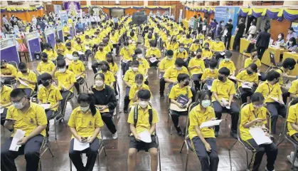  ?? ARNUN CHONMAHATR­AKOOL ?? Students aged between 12-17 years at Surasak Montri school in Din Daeng district yesterday sit in a queue as they wait to get a Pfizer Covid-19 vaccinatio­n.