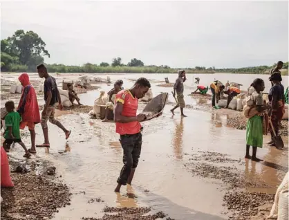  ??  ?? SAKARAHA, Madagascar: Malagasy workers from an informal Sapphire mine seep soil through a strainer in the waters of a river looking for gems on the outskirts of Sakaraha, Madagascar. —AFP photos