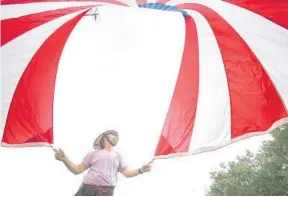  ?? PHOTOS BY STEPHEN M. DOWELL/ORLANDO SENTINEL ?? Firefighte­r Jason Hollenback unfurls a huge American flag before a graduation ceremony for new Orange County Fire Rescue recruits Friday at Valencia College’s Performing Arts Center.