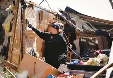  ?? YI-CHIN LEE/HOUSTON CHRONICLE ?? Storm damage: Ernest Ayala collects items from his mother’s destroyed home Wednesday in Pasadena, Texas. A powerful storm system Tuesday spawned tornadoes around Houston. The same system Wednesday dumped about six inches of snow on Detroit and is expected to bring damaging winds to Florida, Georgia and the Carolinas.