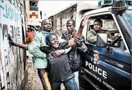  ?? MARCO LONGARI/GETTY-AFP ?? The mother of a Kenyan man shot in the head tries to get to a police van carrying her son’s body Wednesday in Nairobi, the capital. Clashes broke out after Tuesday’s election.