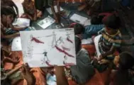  ??  ?? A Rohingya boy at the Balukhali refugee camp holds up a drawing about his experience­s while fleeing Burma.