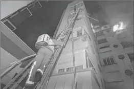  ??  ?? A fireman climbing up a ladder as a fire burns in a building in Erlanger street in Paris.