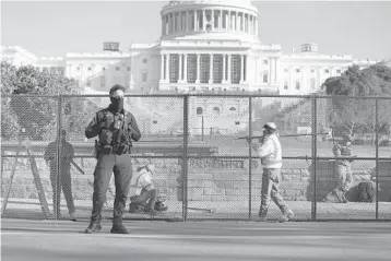  ?? JOE RAEDLE/ GETTY ?? Workers erect a fence Thursday around the U. S. Capitol, one day after a pro- Trump mob broke into the building. Many highprofil­e allies of the president spoke out in defense of him in spite of mayhem that he urged Wednesday.