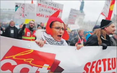  ??  ?? Una mujer grita consignas en una manifestac­ión como parte de la huelga general de empleados de servicios públicos, en la ciudad de París