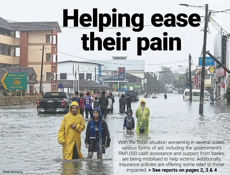  ?? ?? Photo: Bernama
Life goes on: People wading through floodwater­s in Pasir Puteh, Kelantan.
