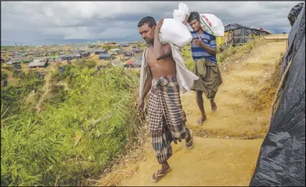  ?? AP PHOTO ?? Rohingya Muslims who crossed over from Myanmar into Bangladesh, walk back to their shelters after collecting aid in Taiy Khali refugee camp in Bangladesh yesterday.