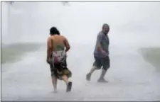  ?? DAVID J. PHILLIP - THE ASSOCIATED PRESS ?? Antonio Barron, right, looks back to his girlfriend, Melissa Rocha, as they run through the street during a band of heavy rain from Hurricane Harvey Saturday, in Palacios, Texas.