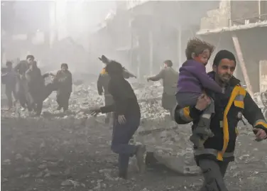  ?? Abdulmonam Eassa / AFP / Getty Images ?? A man carries a child injured in government bombing of the rebel-held eastern suburbs of Damascus.