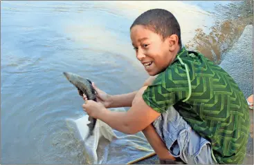  ?? Doug Walker / Rome News-Tribune ?? Armuchee third-grader Tristan Sexton shows off a lake sturgeon to a classmate just before releasing it into the Oostanaula River on Thursday. Youngsters from two classes at the school released close to a thousand of the fish into the river.