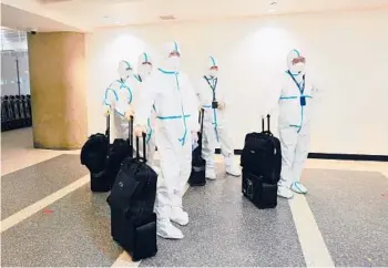  ?? FREDERIC J. BROWN/GETTY-AFP ?? A flight crew from Air China arrive in hazmat suits Friday at Los Angeles Internatio­nal Airport.