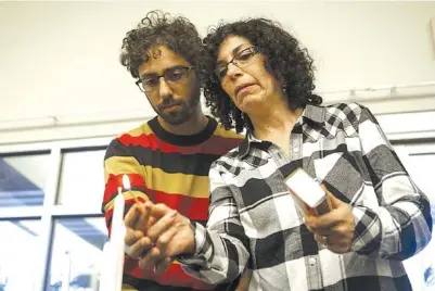  ?? STAFF PHOTO BY C.B. SCHMELTER ?? Isaac Fisher, left, and Randi Weiss light a candle for Cecil Rosenthal. It was the first of 12 candles lit during a prayer vigil held for the Tree of Life Synagogue in Pittsburgh at the Jewish Cultural Center on Monday in Chattanoog­a. Fisher grew up in the Tree of Life Synagogue, and Weiss is a former teacher there.