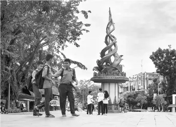  ??  ?? Students stand near a sculpture, symbolisin­g Riau province’s fight against graft, in Pekanbaru, Riau province. — AFP photo