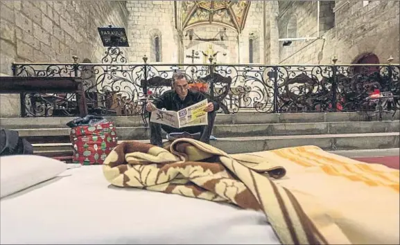  ??  ?? Mi bolsa, mi cama, mi altar. José Carlos hojea un periódico mientras hace tiempo para acostarse, en la nave central del templo