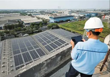  ?? — Reuters ?? Balancing its acts: An engineer checks electrical power from the solar panels that are installed on the roof of a factory in Bekasi. Indonesia wants to strike a balance between boosting economic growth and developing green energy.