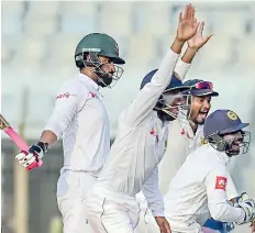  ??  ?? Sri Lanka wicketkeep­er Niroshan Dickwella (R) celebrates with his teammates after the dismissal of Bangladesh­i opener Tamim Iqbal (L). Sri Lanka is aiming a victory as the final day approaches - AFP