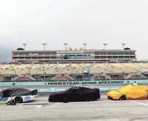  ??  ?? Cars are covered during a rain delay at the NASCAR Dixie Vodka 400 Sunday in Homestead, Fla. The race ended too late for this edition.