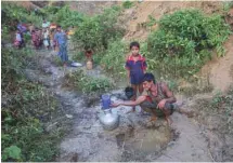  ?? DAR YASIN ASSOCIATED PRESS ?? Un père rohingya et son fils puisent de l’eau de pluie au camp de réfugiés Balukhali, à la frontière du Bangladesh.