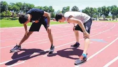  ?? ADOLPHE PIERRE-LOUIS/JOURNAL ?? Alejandro Goldston, left, and Abram Schaap stretch on the Albuquerqu­e Academy track while training for the upcoming Junior World Championsh­ips.