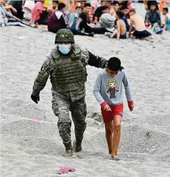  ?? Foto: Antonio Sempere/EUROPA PRESS/dpa ?? Ein spanischer Soldat begleitet ein Kind nach seiner Ankunft in Ceuta. Innerhalb von 36 Stunden gelangten rund 8.000 Menschen in das kleine Gebiet im Nordwesten von Marokko.