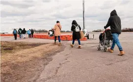  ?? Spencer Platt/Getty Images ?? Recently arrived migrants walk from their temporary tent shelters at Floyd Bennett Field, a former airfield in Brooklyn, Thursday in New York City.