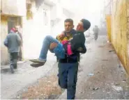  ?? SYRIAN CIVIL DEFENSE WHITE HELMETS VIA AP ?? A member of the Syrian Civil Defense group carries a young man who was wounded Saturday during airstrikes and shelling by Syrian government forces, in Ghouta, Syria.