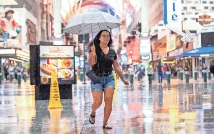  ?? ?? TOP: A woman runs through the rain on Fremont Street in downtown Las Vegas, Aug. 19. As Hurricane Hilary approaches, Nevada Gov. Joe Lombardo activated 100 National Guard troops to Southern Nevada, late Friday.