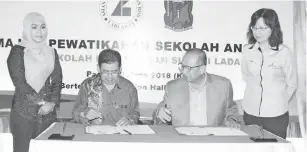  ??  ?? HARRIS (dua kanan) bersama Maidan menandatan­gani watikah Sekolah Angkat SK Sungai Lada dengan ASB.