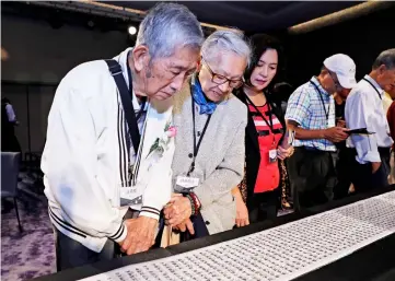  ??  ?? Family members look at a name list of some 1,270 people from the island’s ‘White Terror’ purges during a ceremony in Taipei to formalise the victims’ pardons. — AFP photo