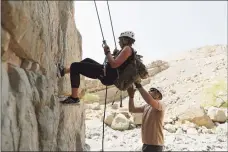  ?? Associated Press ?? One of the guests rappels down a rock mountain during a survival trial at the Jebel Jais, northeast of Ras al- Khaimah, United Arab Emirates, on Thursday.