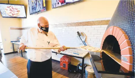  ??  ?? Tim Widrick, one of the owners and chef of the restaurant, places one of his homemade pizzas in in the brick oven Thursday at SURV in Forks Township.RICK KINTZEL/MORNING CALL PHOTOS