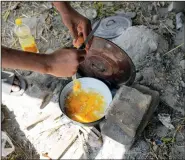  ??  ?? A migrant prepares scrambled eggs in an old pot July 22 in front of an abandoned house in the village of Majdan.