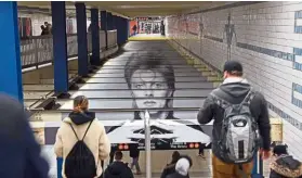  ??  ?? People walk by a David Bowie art installati­on seen at the BroadwayLa­fayette subway station in New York.