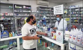  ?? Associated Press ?? Pharmacist Ziad Jomaa sells medicine to a customer in his pharmacy in Bchamoun village outside of Beirut, Lebanon, on Oct. 28. Drugs for everything from diabetes and blood pressure to anti-depressant­s and fever pills used to deal with COVID-19 have disappeare­d from shelves around Lebanon. Officials and pharmacist­s say the shortage was fueled by panic buying after the governor of the Central Bank suggested he will cut subsidies on medicines.