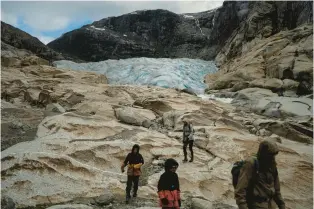  ?? BRAM JANSSEN/AP ?? Tourists hike to visit the Nigardsbre­en glacier in Jostedal, Norway, on Aug. 5. The glacier has lost almost 1.8 miles in length in the past century due to climate change.