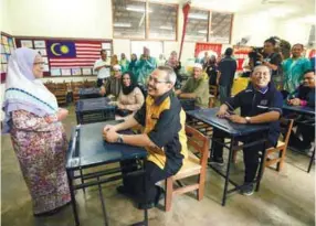  ??  ?? Dzuklifli sitting at the very desk of his former class of Standard 3M of SK Hashim Awang when he was a student there in 1979. Chatting with him is Mariam.