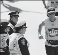  ?? The Associated Press ?? BOSTON BOMBING FILMS: Actor Mark Wahlberg, center left, dressed as a Boston Police officer, watches runners cross the finish line as he films a scene for his “Patriot’s Day” movie at the 120th Boston Marathon in Boston.